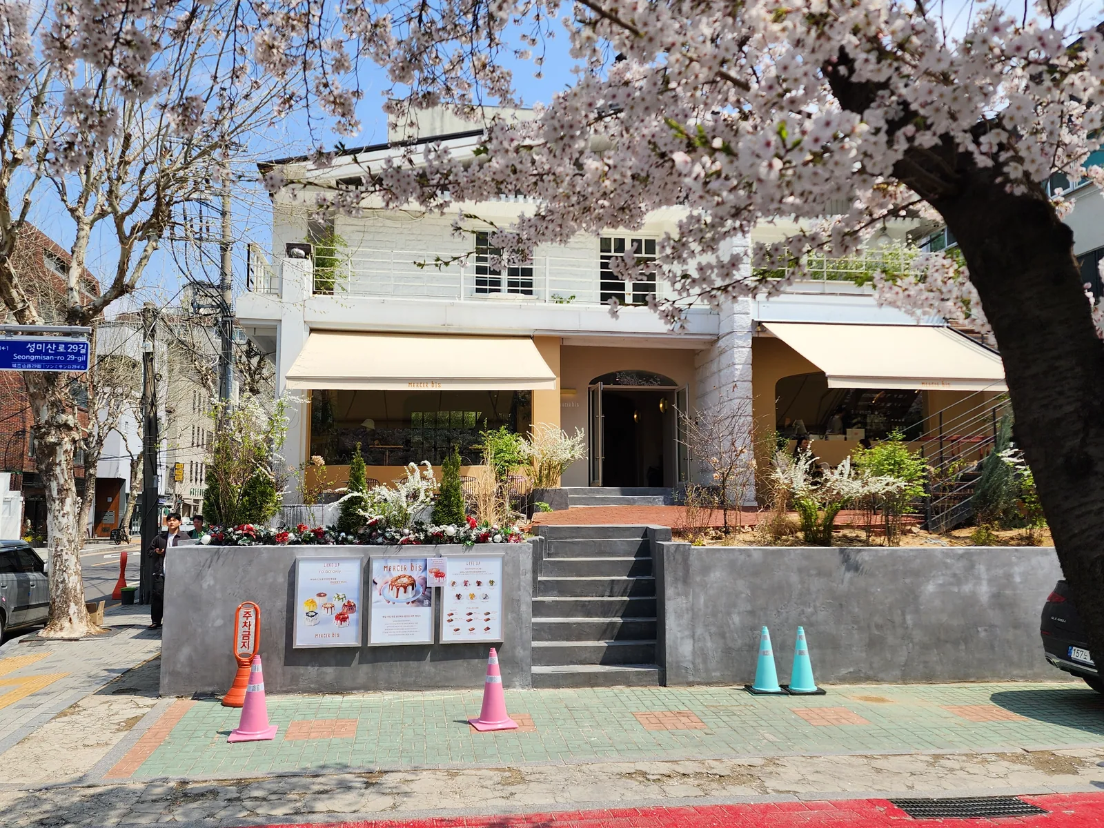마사비스 연남점 외관 — 벚꽃 아래 흰 2층 건물과 크림색 어닝, 돌계단과 화단